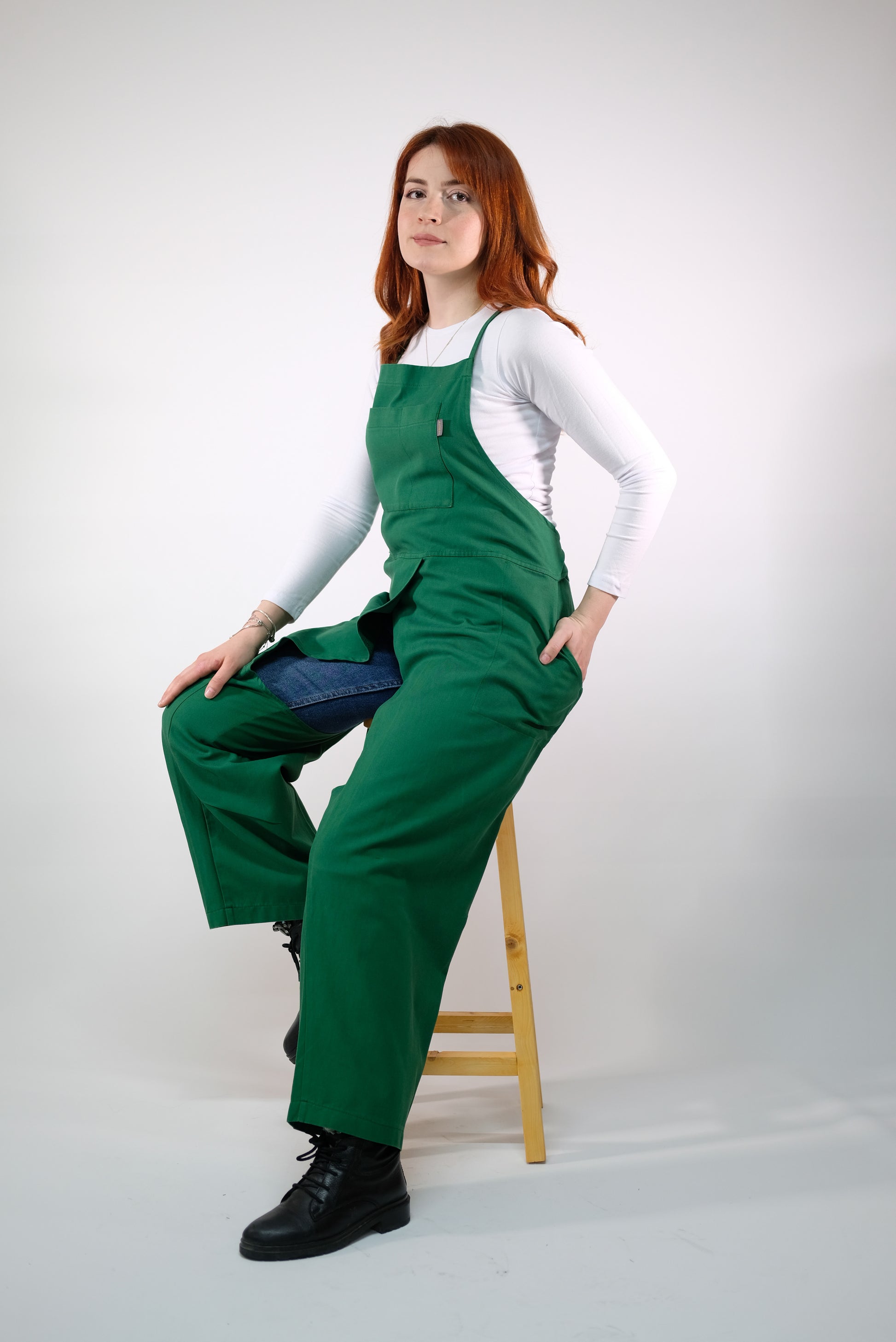 Green backless jumpsuit apron displayed on mannequin, showing split leg design.