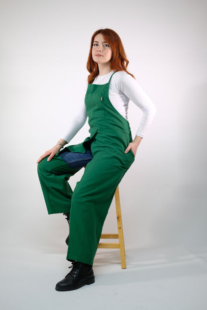 Green backless jumpsuit apron displayed on mannequin, showing split leg design.