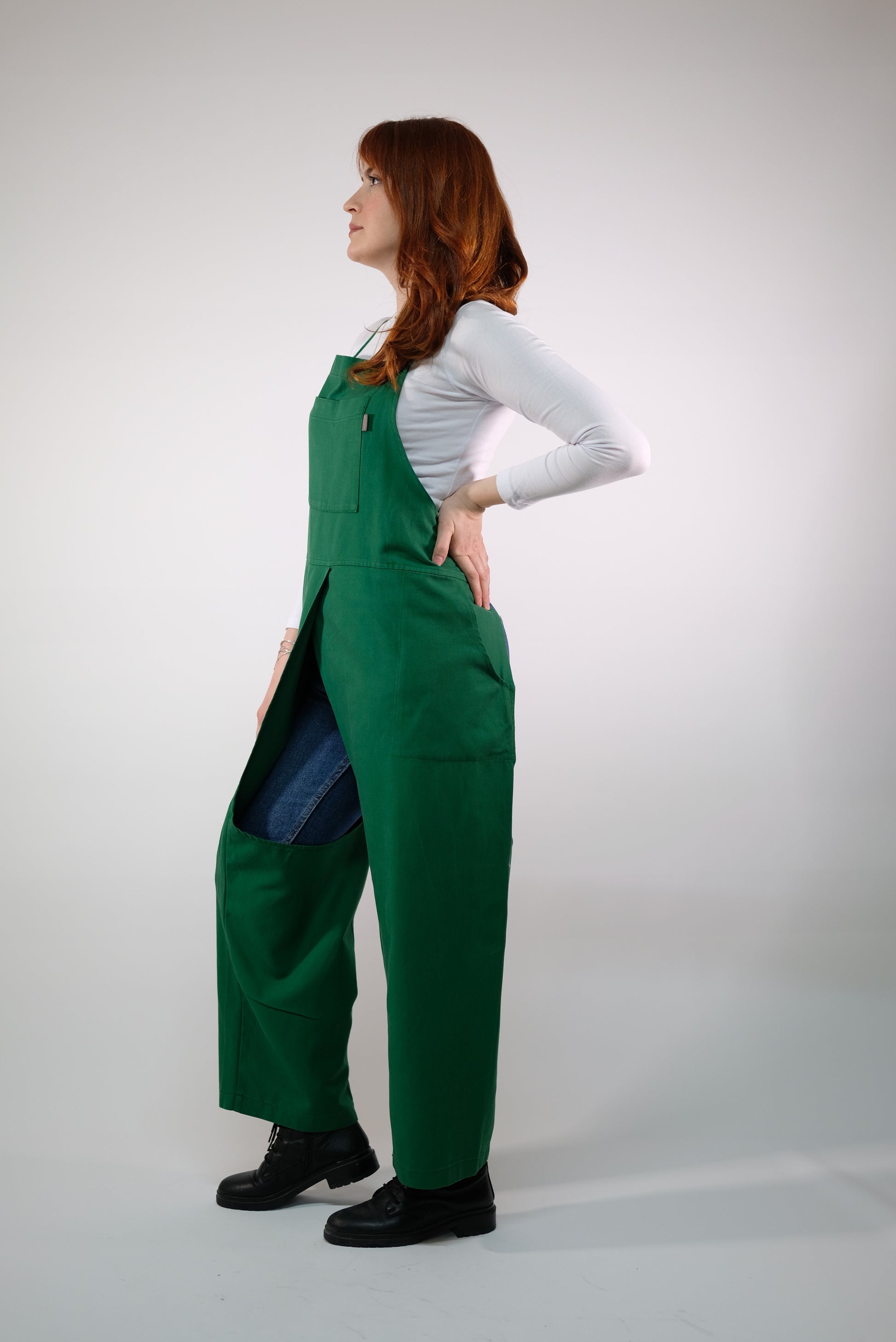 Artist wearing green overall apron while working at pottery wheel.