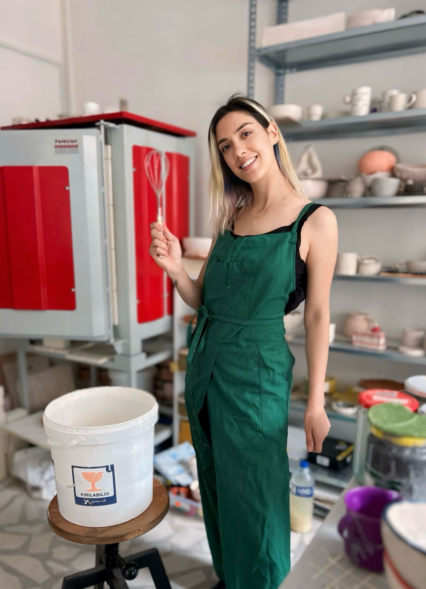Artisan tying apron back straps in pottery studio.