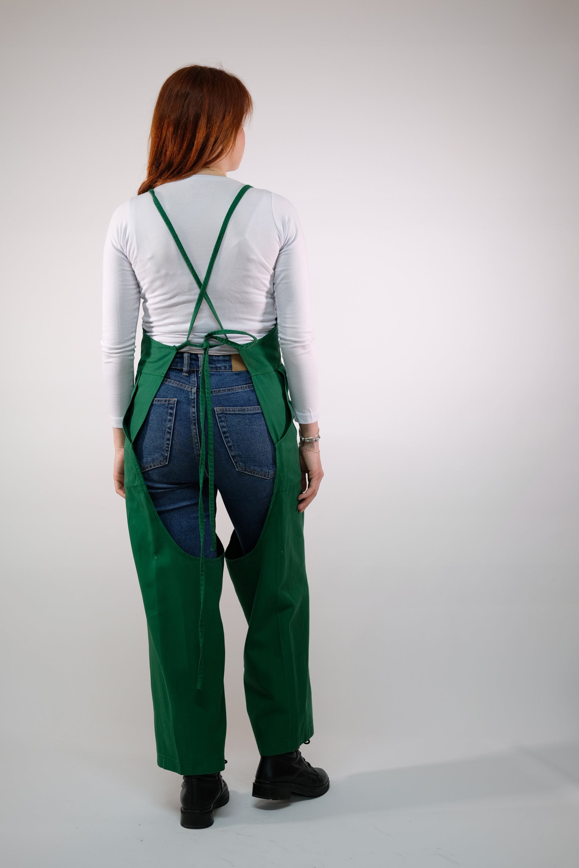 Styled photo: green jumpsuit apron with pottery tools and clay.