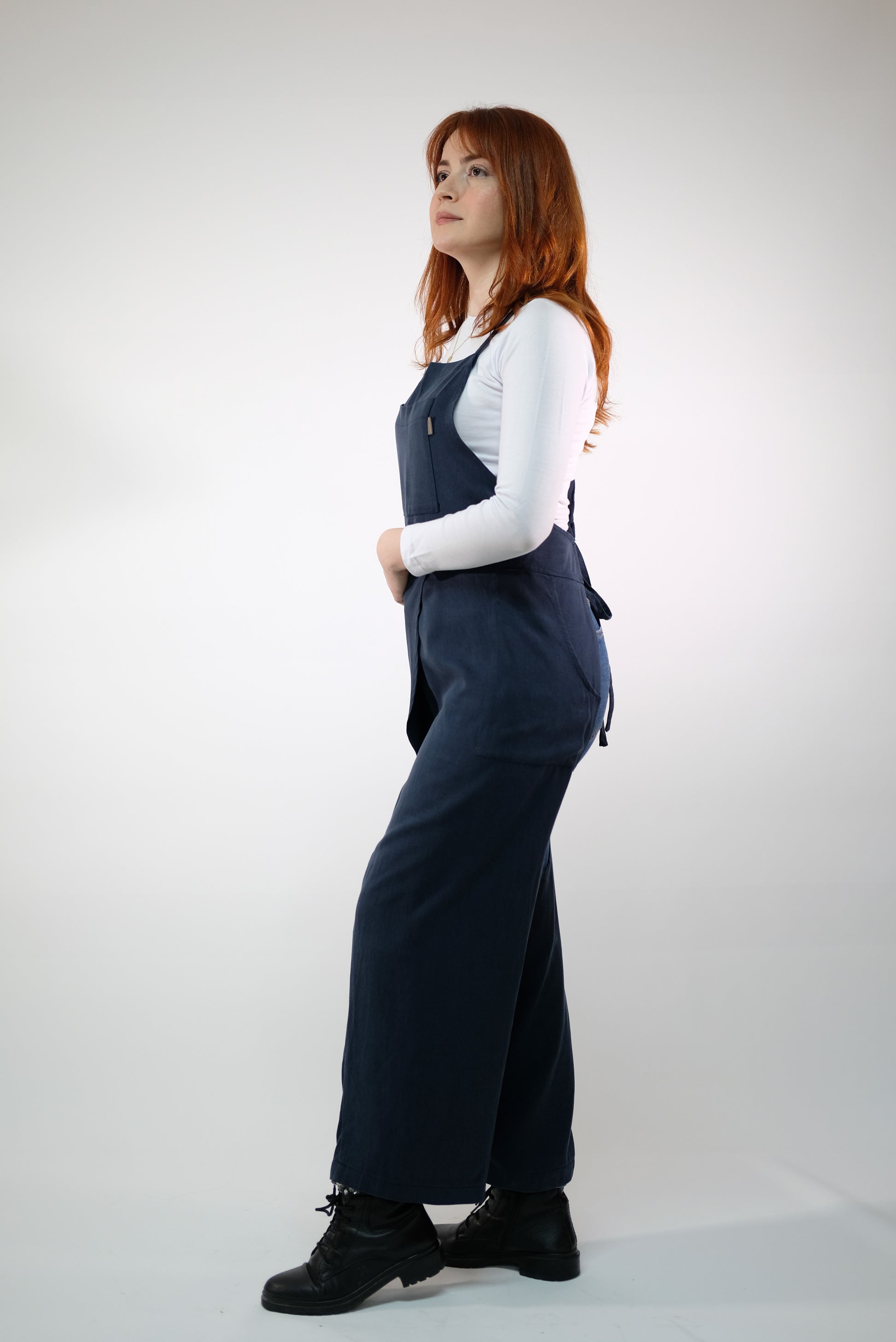 Side pockets on navy apron holding pottery essentials.