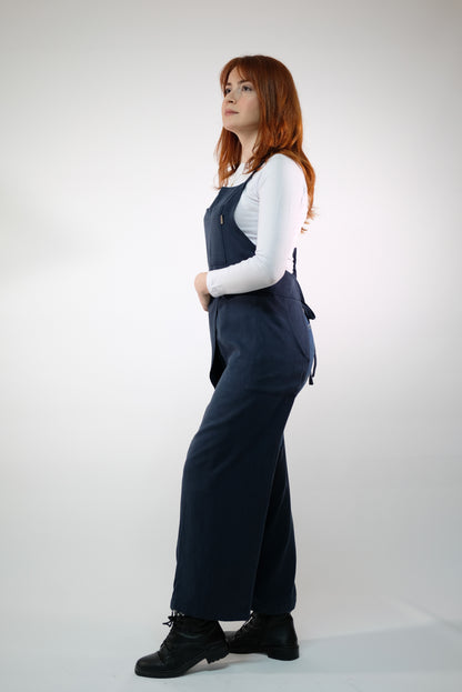 Side pockets on navy apron holding pottery essentials.